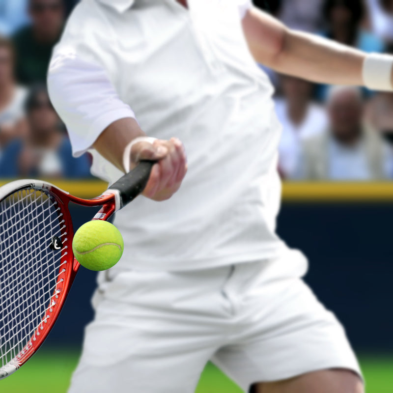 Tennis player hitting high-visibility green tennis ball with Redcat™ Eyewear LumiGlo™ lenses.